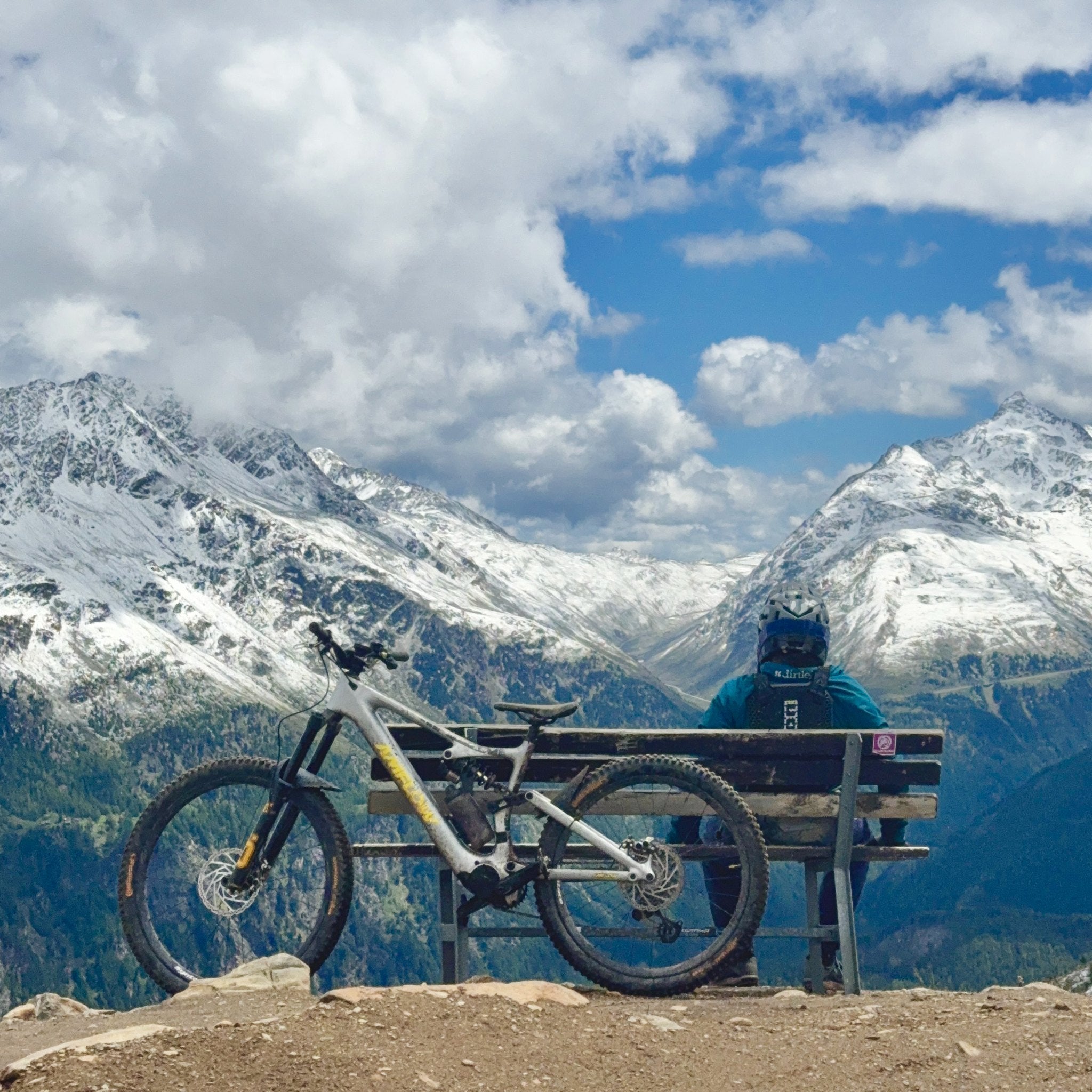 Mountainbiker auf einer Bank mit Blick auf die verschneiten Alpen – Bike Republic Sölden